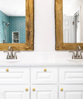 Level Up Your Kitchen Setup With This 25 Pack Of Heavy Duty Brushed Brass Cabinet Knobs Measuring 1-1/4 Inch Round Circle For A Sophisticated Vibe And Real Nice Upgrade To Any Drawer Or Vanity Project, shown on a white vanity with mirrors.