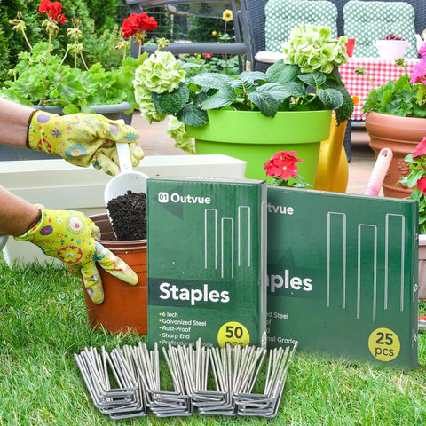 Gardening scene with Six Inch Landscape Staples Set Of Fifty Durable 11 Gauge Garden Stakes in packaging and loose, in front of potted plants.