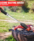 Silicone basting brush applying sauce on grilled meat outdoors from Heavy Duty BBQ Tool Set With Premium Stainless Steel Spatula Fork Brush And Tongs For Grilling Lovers Outdoors A Top Notch Gift Idea For Men And Women Who Live For The Grill.