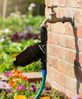 Heavy Duty Three Quarter Inch Inline Hose Filter For Drip Irrigation With 120 Mesh Screen, attached to a spigot in a garden.
