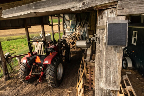 Run Forever Solar Panel With Built In High Capacity Battery For Trail Cameras mounted on a wooden post near tractors.