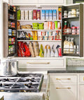 Open kitchen cabinet with a stocked pantry of snacks and spices next to an oven and pot on the stove.