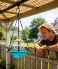 Man observing Solar Bird Bath Fountain With Hanging Cascade Water Bowl And Pump Outdoor Garden Decor For Hummingbirds Easy Sun Powered Water Feature That Runs On Direct Sunlight No Batteries Needed Blue hanging under pergola
