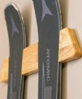 Close-up of Dope Horizontal Wood Ski Rack Wall Mount With Calibrated Brackets Natural Oak Finish holding skis on the wall.