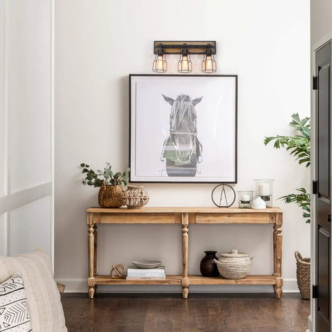 Two Light Farmhouse Vanity Light With Vintage Black Metal Cage And Rustic Wood Finish, E26 Base, Perfect For Bathroom, Kitchen, Hallway Or Bedroom, Open Cage Design For That Dope Industrial Cozy Vibe mounted above artwork in hallway.