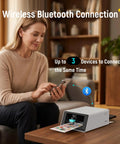 All In One Color Sticker Printer And Cutter For DIY Crafters And Custom Labels And Gifts With Thermal Dye Sublimation 300 DPI And Precise AI Auto Cutting on a table, woman using smartphone to connect via Bluetooth.