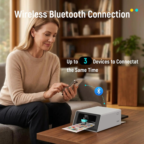 All In One Color Sticker Printer And Cutter For DIY Crafters And Custom Labels And Gifts With Thermal Dye Sublimation 300 DPI And Precise AI Auto Cutting on a table, woman using smartphone to connect via Bluetooth.