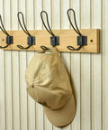 Super Sturdy Wall Mounted Coat Rack With Four Heavy Duty Hooks To Keep Clutter In Check Holds a cap on a wooden rack.