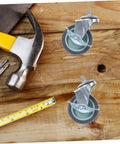 Hella Durable Smooth Operator Four Piece Heavy Duty Swivel Caster Wheels With Threaded Stem Attachment And Secure Lockable Brakes on wood surface with tools.
