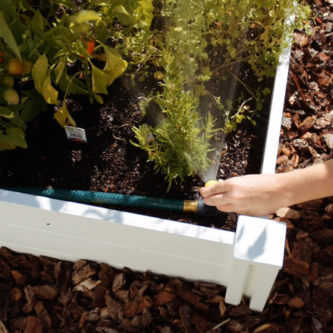 Person adjusting Three Pack Multi Adjustable Spike Sprinklers With Quick Connect Bundle in garden bed