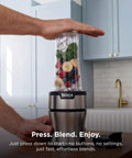 Heavy Duty Personal Blender Featuring 900W Push To Blend Motor And Pro Extractor Blades Crushing Ice For Nutrient Dense Smoothies Including Three Grab And Go 20 Oz Serveware Cups In Classic Silver with fruits and spinach ready for blending.