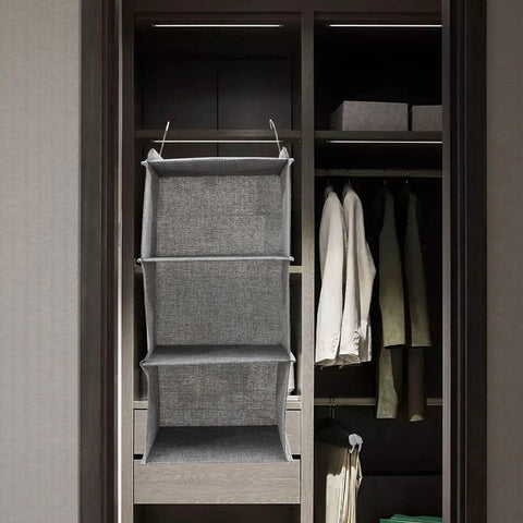 Three Tier Hanging Wardrobe Organizer With Slick Foldable Linen Fabric And Heavy Duty Hooks For Ultimate Closet Space Saving and Dorm Game Changer Essentials in grey, showcasing three compartments in a closet.