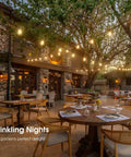 50Ft Outdoor String Lights With 27 Edison Dimmable LED Bulbs Weatherproof And Shatterproof illuminating a patio with trees and tables