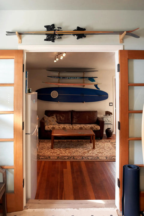 Top Shelf Heavy Duty Bamboo Ski Wall Mount Rack For Garage Storage displaying skis above a door in a cozy lodge.