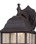 Solid Exterior Wall Lantern Featuring Slick Weathered Patina Cast Aluminum Body Plus Crisp Seeded Glass Panes close-up view with ornate top detailing.