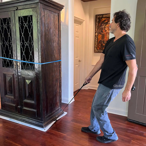 Man using Giant Appliance Slider With Pull Strap Slide Heavy Load Single Hand Shield Surfaces Easy Roll For Ovens Dishwashers Dryers Toolboxes Plus Massive Floor Glide Mat For Serious Moves Pack Of One to move a wooden cabinet.