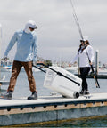 Couple using MaxCold Glide 110 Qt Insulated Rolling Cooler With Soft Ride Wheels on dock with telescoping handle.