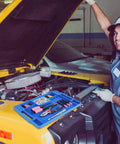 Mechanic using Blue Silicone Tool Tray For Auto Repairs Flexible Magnetic Tool Holder With Small Parts Tray on yellow vehicle