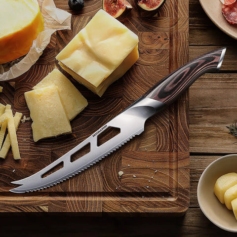 Five Inch Serrated Cheese Knife Crafted With Premium Steel Core And A Super Slick Hollow Blade For Butter Smooth Cuts That Slide Off Easy Plus A Gotta Have Fork Tip For Zero Mess Party Spread on a wooden cutting board with cheese.