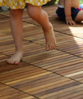 Children playing on EZ-Floor Interlocking Teak Flooring Tiles With Solid Teak Wood Oil Finish Long Slat Set Of 10 Easy DIY Installation