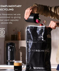 Person recycling capsules next to Vertuo Plus Coffee And Espresso Maker By Breville Grey One Button Brew For Coffee Or Espresso No Fuss Easy Button Brew 25 Second Heat Up And Energy Saving Auto Shut Off Delivers Rich Flavor At Home. Recycling bag in focus.