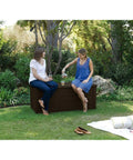 Two people sitting on Lockable 120 Gallon Outdoor Storage Deck Box For Patio Backyard And Garden In Brown Waterproof Plastic Bench