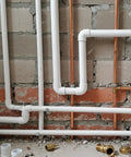PVC and copper pipes installed on brick wall, plumbing setup in construction site