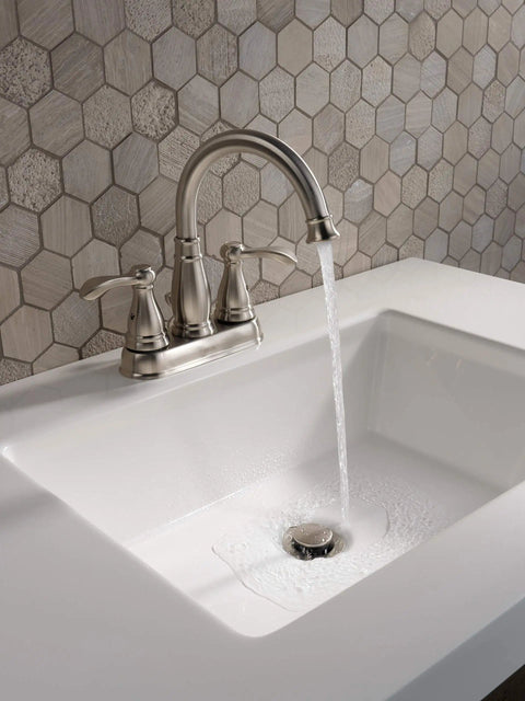 Porter Two Handle Centerset Bathroom Faucet In Brushed Nickel With Mid Arc Spout running water into sink