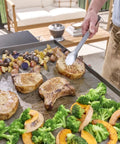 Chef using 24 Piece Griddle Tool Set With Storage Tote Stainless Steel Flat Top Grill Accessories to cook vegetables and meat.