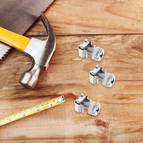 Three nickel plated M6 rack mount cage nuts on wooden surface with hammer and measuring tape for server rack assembly.