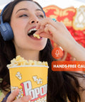Person wearing Wireless Bluetooth Cans With Up To 40 Hours Battery, Built-In Microphone For Calls while eating popcorn.