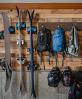 Ski And Snowboard Wall Mount Rack For Garage And Home Storage with skis, poles, and backpacks mounted on a wooden wall.