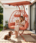 Double Egg Chair With Stand And Adjustable Canopy For Indoor Outdoor Use Cozy 2 Person Wicker Hanging Swing Chairs With Removable Cushions 660 Lbs Capacity Patio Balcony Orange Red Frame And Cushions on a patio with a woman and child sitting