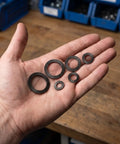 72 Piece Set Double Tooth Lock Washers Black Ironclad Grip 65mn Steel Self Locking Wedge Hardware in hand for trucks and gear.