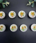 Kick Up Your Rustic Style With Eight Darn Cute Ceramic Kitchen Cabinet Drawer Knobs Featuring Pretty Sunflower And Butterfly Art For Dressers And Cupboards Designed For Smooth Grip Easy Install And Farmhouse Vibes - Set of eight glossy ceramic knobs with floral designs.