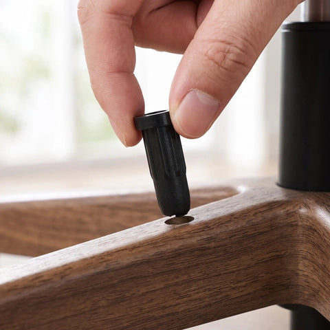 Person inserting Fifty Pack Black Nylon Caster Stem Socket Sleeve With Secure Grip Neck For Office Chair Leg Swap Bushing into furniture.