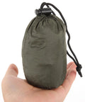 Hand holding green carry bag for Emergency Blanket Set With Green Aluminum Thermal Rescue Blanket And A Carry Bag For Camping And Hiking Survival Warmth In Outdoor Emergencies Lightweight And Compact With A Foldable Carry Bag For Hiking Camping Running And Disaster Prep.