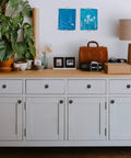White cabinet with 60 Pack Matte Black Zinc Kitchen Cabinet Knobs And Drawer Pulls For Dressers installed on doors and drawers.