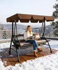 Woman reading on a three seat outdoor patio swing chair with large convertible canopy porch glider hammock lounge chair for porch rattan wicker steel frame cushions and pillows brown, on a snowy deck.