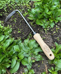 Three Piece Weeding Kit With Disc Weeder, Cape Cod Weeder, And Weedpopper in use among green plants in a garden.