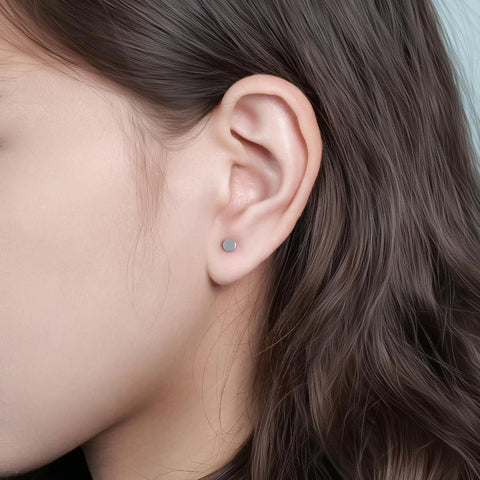 Close-up of Implant Grade F136 Titanium Dot Stud Earrings on earlobe, showcasing secure screw back flat posts.