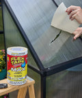 Person applying heavy duty rubberized waterproof tape to patch a greenhouse tear, next to a roll of tape on a stool.