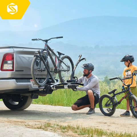 Man installing modular two in one hitch rack for two bikes up to eighty pounds on a truck with child observing, tilts and folds for storage, uses no frame contact, fits standard two inch hitches.