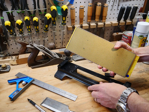 Person placing Double Sided Diamond Sharpening Stone With Base DuoSharp 10 Inch Bench Stone in workshop setting