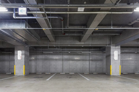 White 5 Pack Surface Mounted Fire Extinguisher Cabinet With Hammer Attachment And Weatherproof Cover in a concrete parking garage.