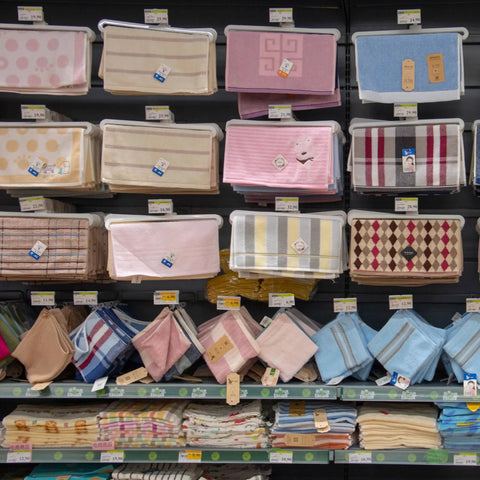Retail display of colorful towels and fabric storage bags on shelves with various patterns and designs.