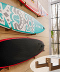 Rugged Wood Surfboard Wall Rack For Indoor Or Outdoor Use Mountable Surfboard Hanger in use, displaying boards in a room.