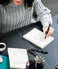 Person writing in a notebook with Goes On Like Butter Gel Pens Black 0.7 Mm Medium Point 12 Pack Featuring Zero Smear Quick Dry Ink.