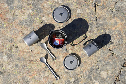 Camping cookware set with Ultralight Titanium Long Spoon For Backpacking And Camping, Durable Camp Utensil, on rocky surface.