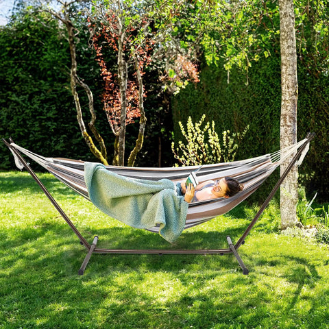Person relaxing on 550 Lbs Capacity Hammock Stand With Portable Carrying Bag Heavy Duty Two Person Frame For Outdoors And Indoors Black Antique Finish